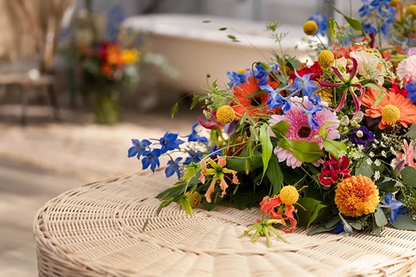 Rouwstuk kleurrijke veldbloemen op uitvaartmand
