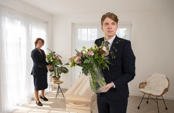 UItvaartmedewerkers houden bloemen vast in kistruimte