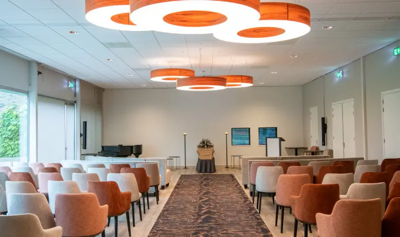 Grote zaal met rijen stoelen en een tapijt in het gangpad
