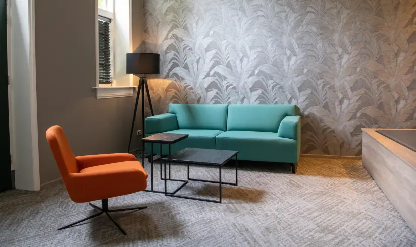 Een kamer met een blauwe bank en een oranje fauteuil