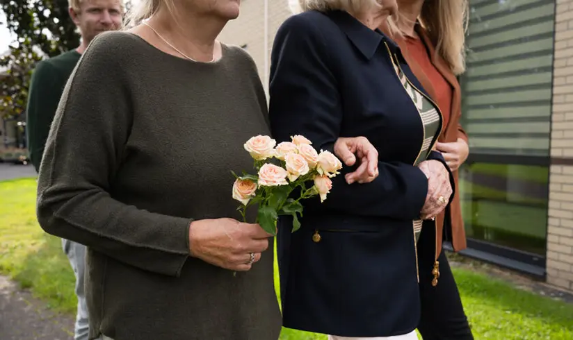 Een groepje nabestaanden loopt buiten met rozen