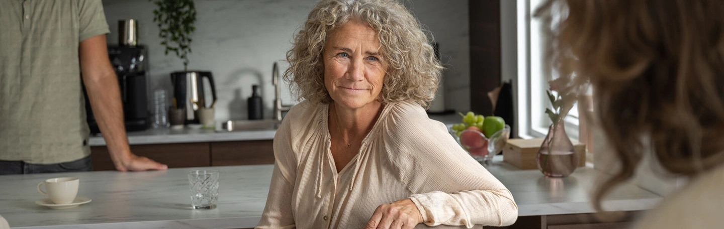 Oudere vrouw met grijze krullen recht in de camera kijkend