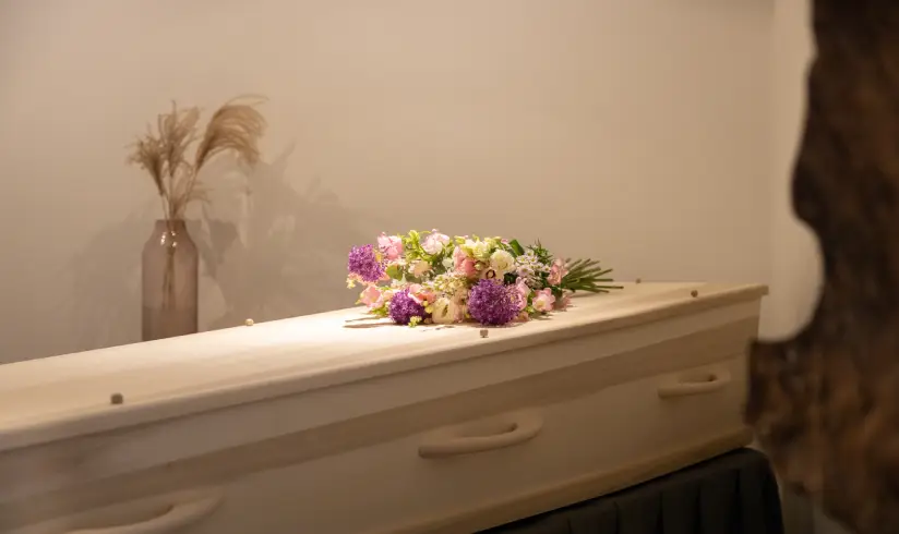 Close up van een houten uitvaartkist met bloemen