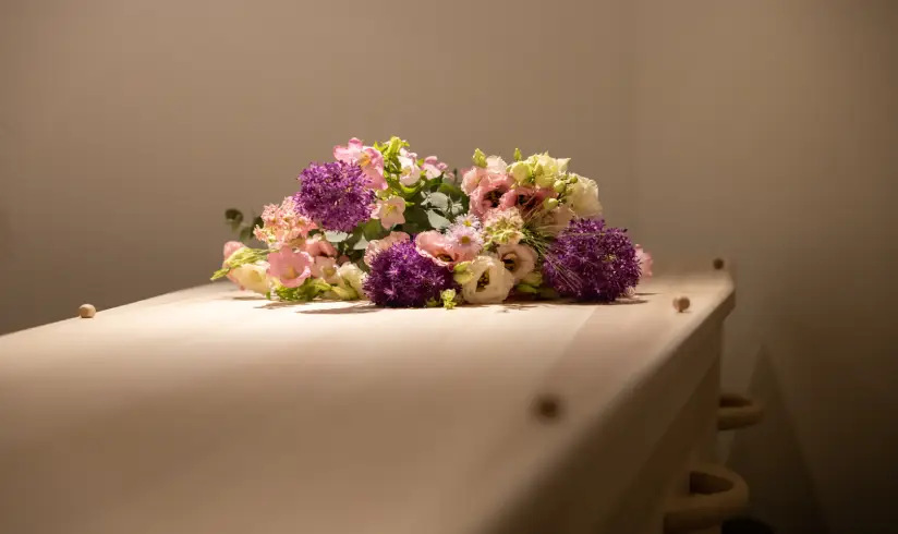Close up van de bovenkant van een uitvaartkist met een bos bloemen