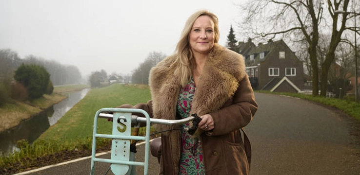 Portretfoto blonde vrouw met fiets op de dijk
