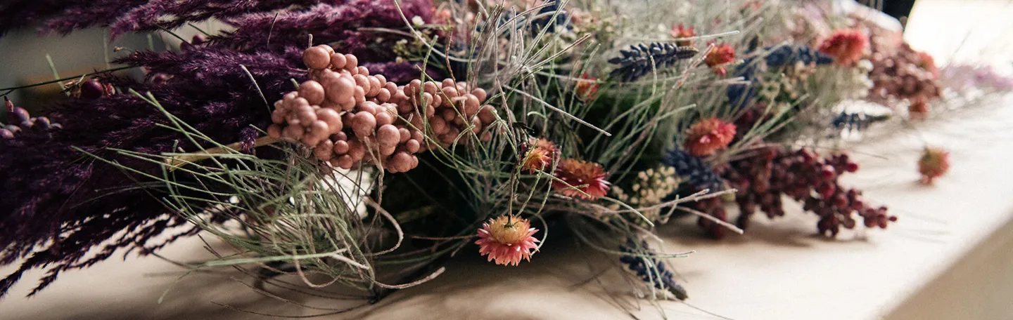 Een close up van een boeket bloemen op een houten uitvaartkist