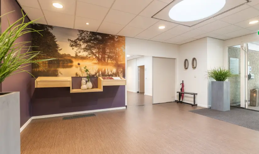 Een gang met een tafel aan de muur voor het condoleanceboek