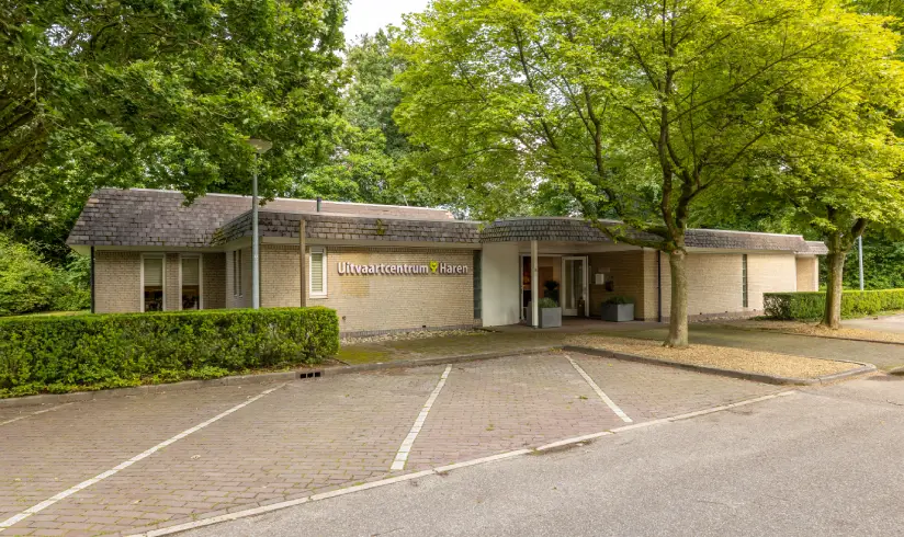 Stenen gebouw omringd door gebouwen met parkeerplaatsen