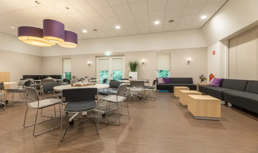 Grote ruimte met een zithoek met banken en tafels met stoelen