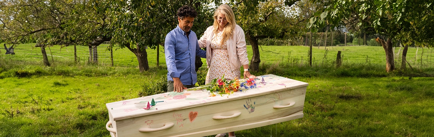 Man en vrouw kijken naar beneden bij kist op een buitenuitvaart