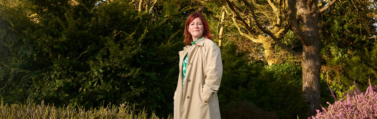 Vrouw met rossig haar staat in natuurgebied met heide