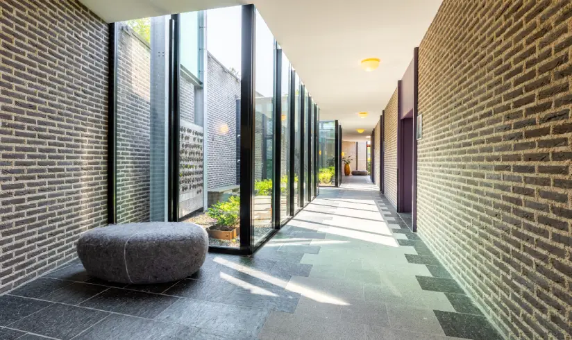 Een gang in een stenen gebouw met glazen wanden