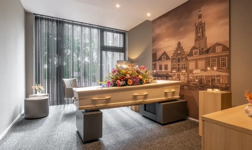 Er staan een kist met bloemen erbovenop in een opbaarkamer in het uitvaartcentrum