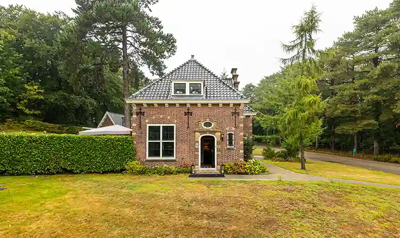 Een stenen gebouw met een grasveld ervoor en bomen aan de zijkanten