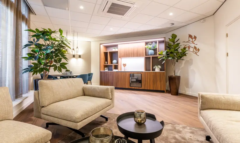 Een kamer met een zithoek met lichte bank en fauteuil
