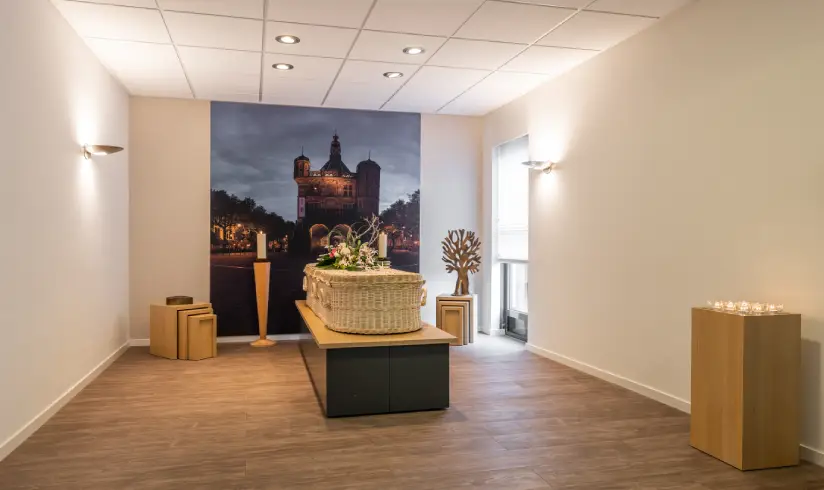 Kamer met een houten uitvaartkist met bloemen en een schilderij