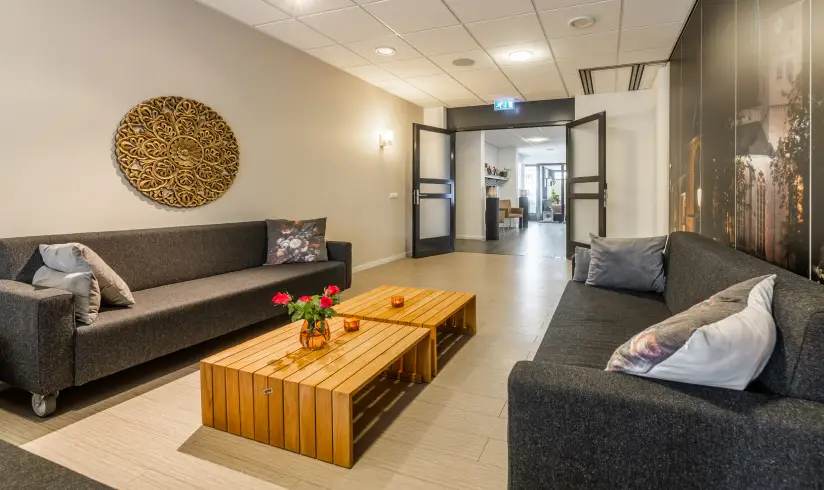 Kamer met grijze banken en 2 houten salontafels