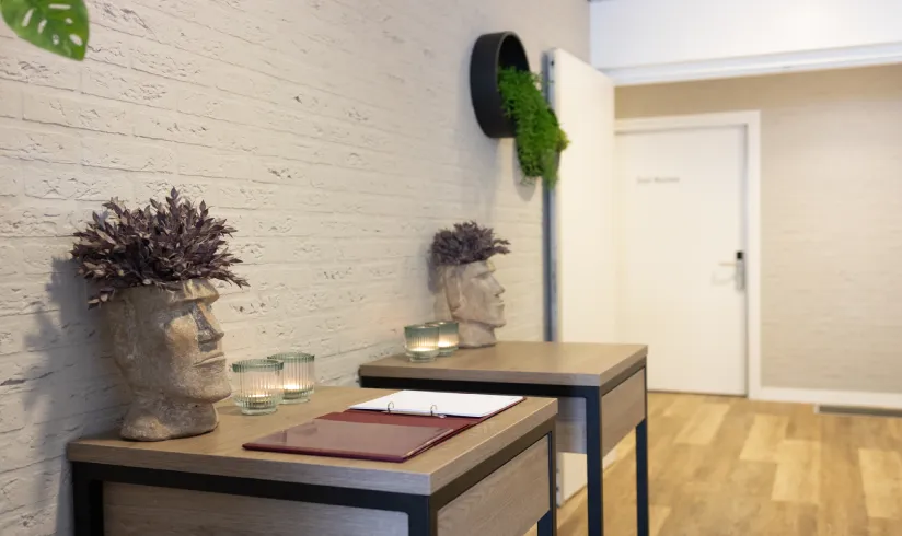 Tafeltjes voor een witte muur met planten en condoleance registers