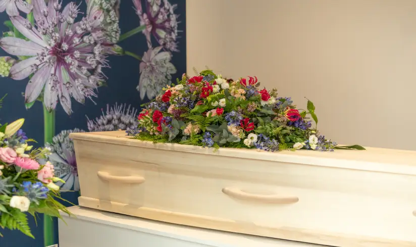 Houten uitvaartkist met bloemen