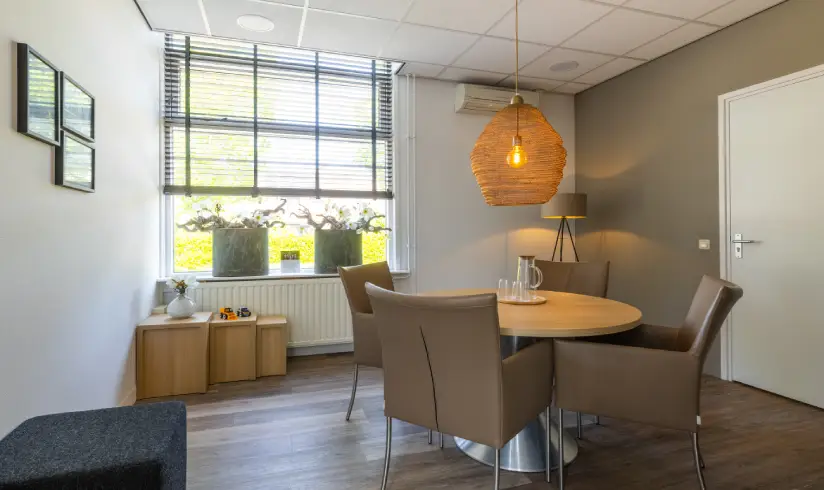 kamer met een tafel met 4 stoelen en een poef