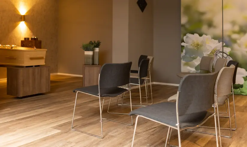 Kamer met een houten uitvaartkist en 2 rijen stoelen