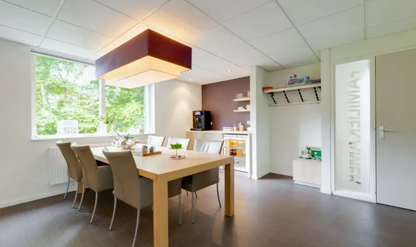 Kamer met een tafel en 6 bruine stoelen eromheen.