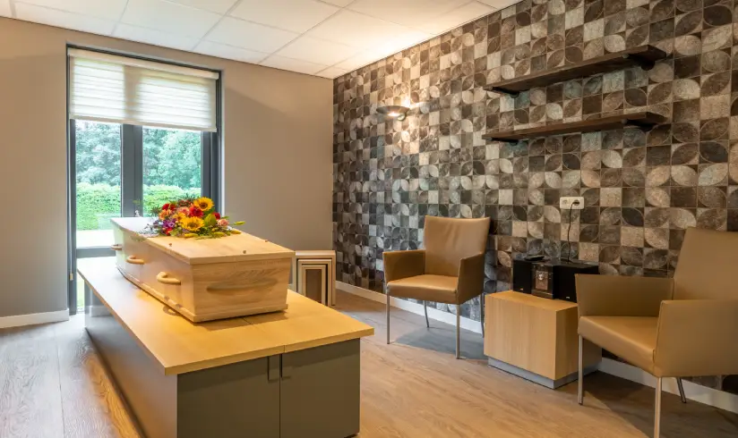 Ruimte met een kist met bloemen en 2 stoelen aan de muur.