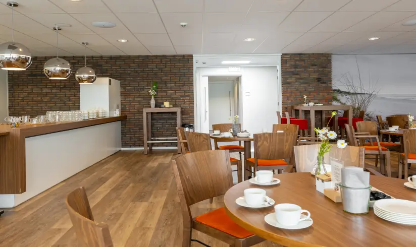 Grote ruimte met tafels en stoelen, kopjes koffie op de tafel