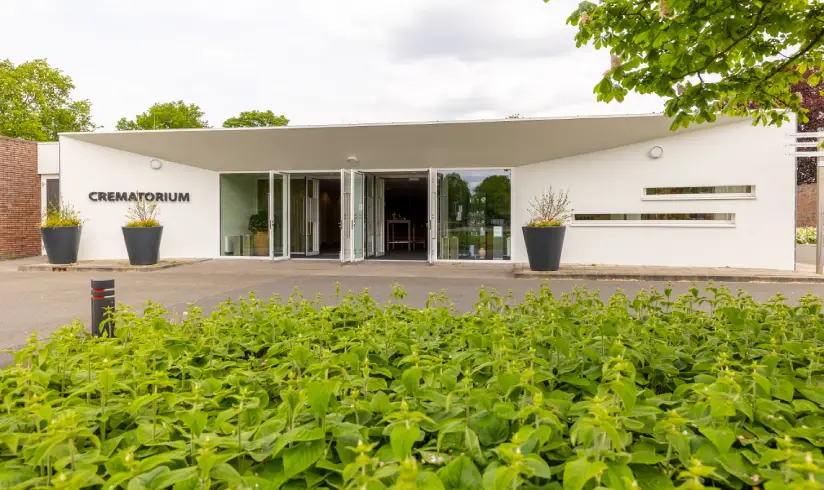 Vooraanzicht van een wit pand met links het woord 'Crematorium'