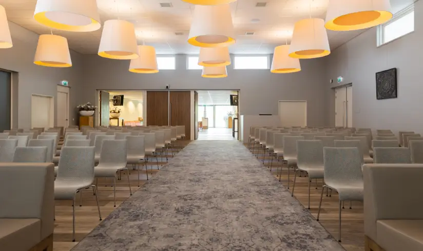 Grote zaal met rijen stoelen en een gangpad in het midden