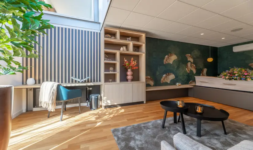 Kamer met een houten uitvaartkist en een zithoek met fauteuils