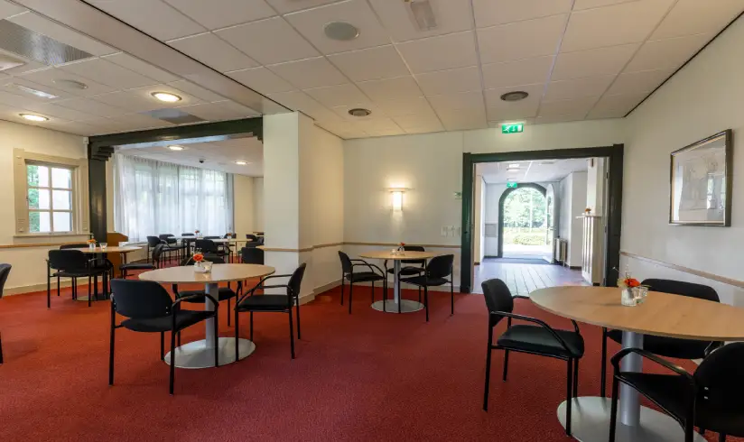 Grote ruimte met rood tapijt met tafels en stoelen