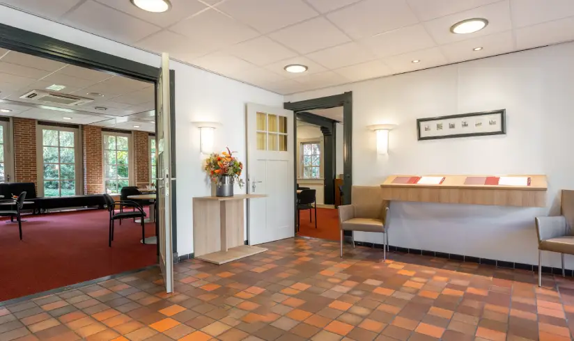 Gang met betegelde vloer en een bureau aan de muur en 2 stoelen