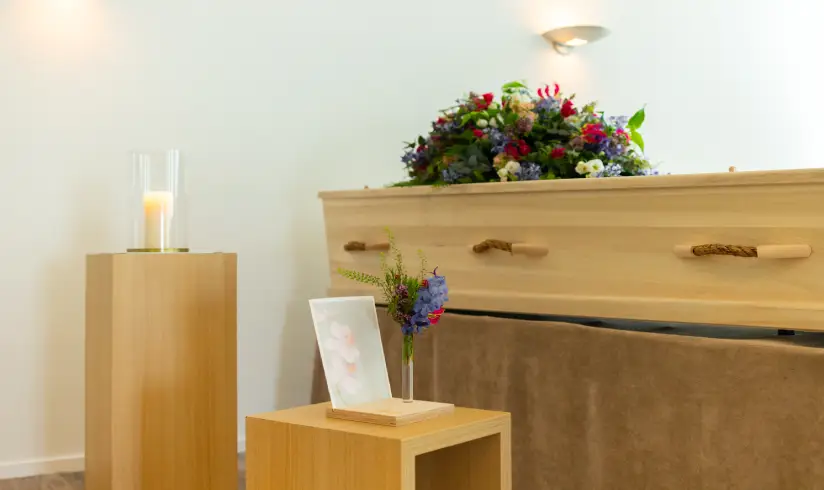 Close up van een houten uitvaartkist met bloemen