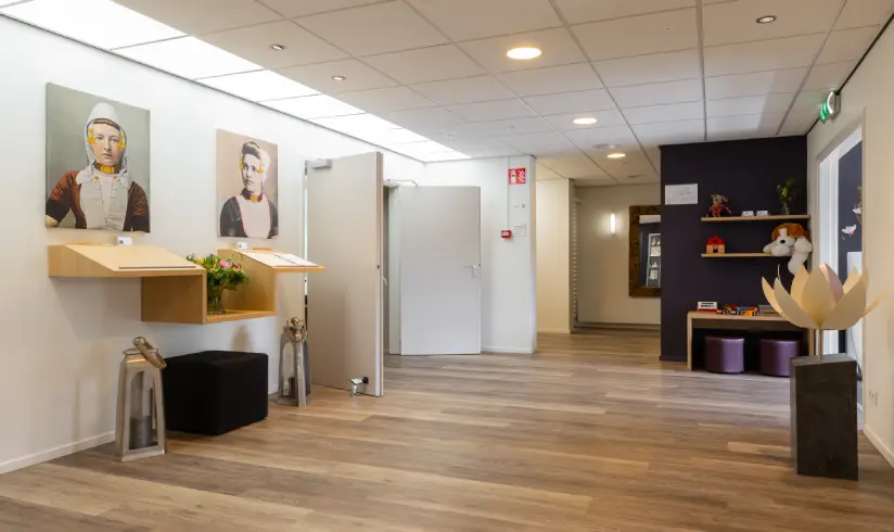 Grote hal met een hoek met speelgoed en aan de muur 2 plekken voor condoleance registers