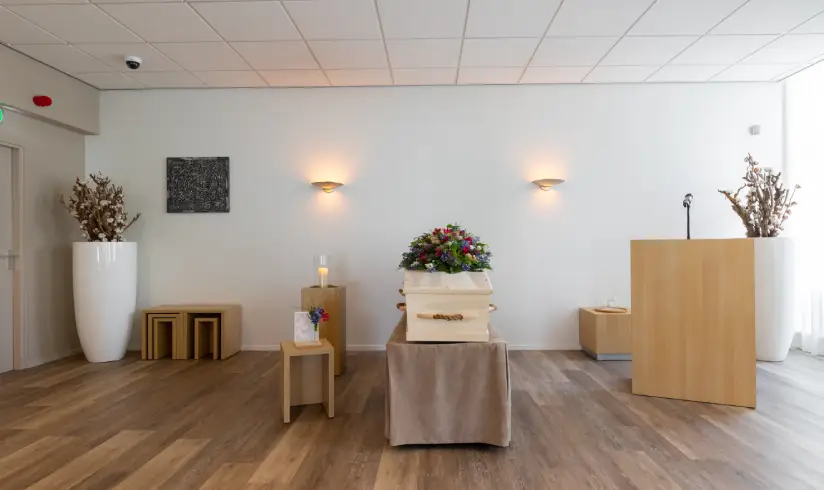 Grote ruimte met een kist met bloemen in het midden en een spreekgestoelte aan de rechter kant