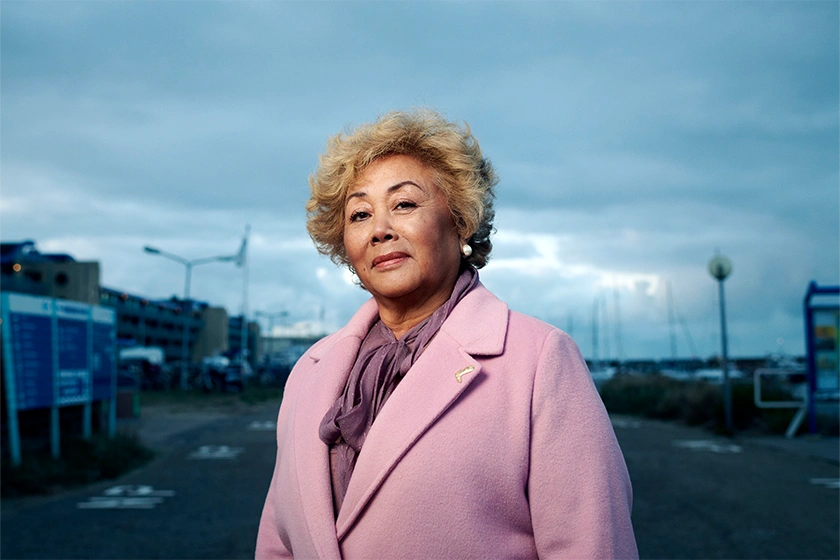 Portretfoto Indonesische vrouw in roze jas met blauwe lucht