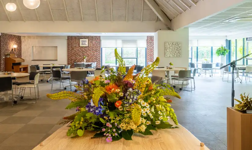 Een kist met bloemen in het midden en tafels en stoelen op de achtergrond