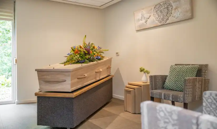 Ruimte met een uitvaartkist en 2 stoelen aan de muren