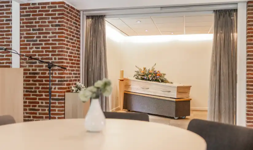 Opbaarkamer met een tafel met stoelen op de voorgrond
