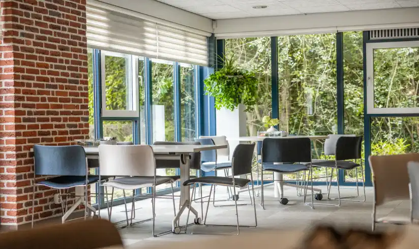 Ruimte met grote ramen en tafels en stoelen