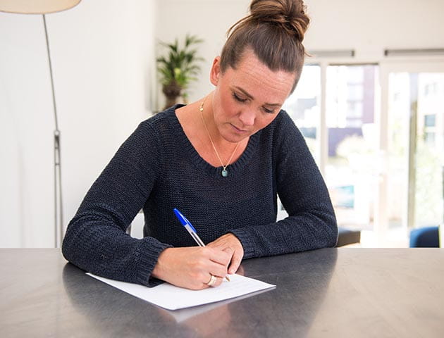 Vrouw schrijft aan tafel een brief