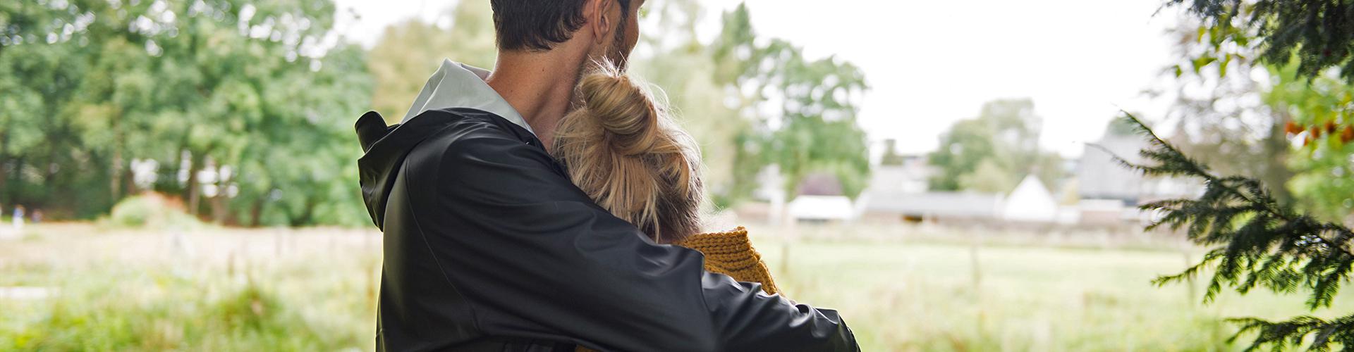 Man knuffelt vrouw in bosrijke omgeving