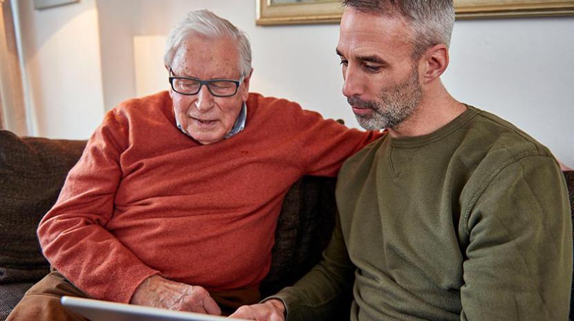 Foto van opa die hulp krijgt met bediening van ipad