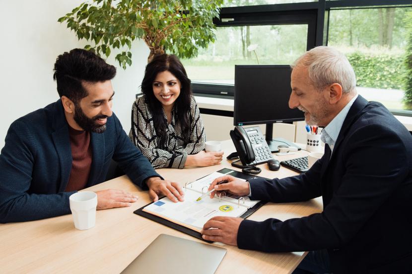 Adviseur aan bureau met twee klanten