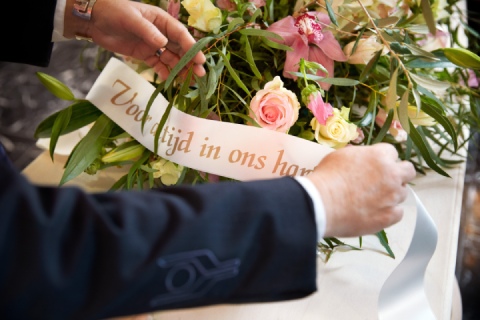 Rouwbloemen worden op kist geplaatst