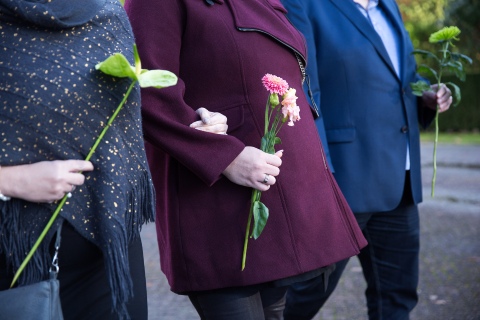 Drie mensen lopen met bloemen in de hand