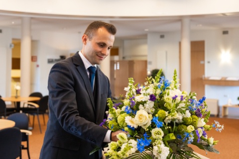 Uitvaartverzorger met bloemstuk uitvaartcentrum Herten